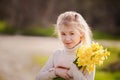 cute blonde happy little girl with yellow daffodils in the spring country Royalty Free Stock Photo