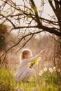 cute blonde happy little girl with yellow daffodils in the spring country Royalty Free Stock Photo