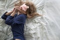 Cute blonde in her bed in blue pajamas and sleep mask. Royalty Free Stock Photo