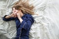 Cute blonde in her bed in blue pajamas and sleep mask, top view Royalty Free Stock Photo