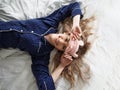 Cute blonde in her bed in blue pajamas and sleep mask, top view Royalty Free Stock Photo