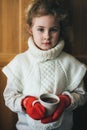 Cute blonde little girl holding hot steaming tea cup close up photo Royalty Free Stock Photo