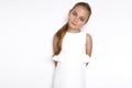 Cute blonde little girl in a white elegant dress, standing on a white background in studio. Royalty Free Stock Photo