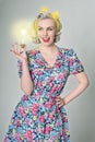 Cute blonde retro girl holding glowing light bulb - humorous concept