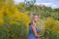 Horizontal closeup portrait of a charming blonde on a background of a blooming field, sky and trees Royalty Free Stock Photo