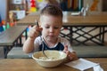 Cute blonde toddler boy eating Dumplings in indoors restaurant. Healthy, unhealthy food for little kids.