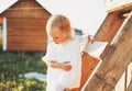 Cute blonde toddler little girl climbs up the ladder, country side, cottagecor Royalty Free Stock Photo