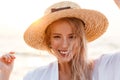 Cute blonde woman wearing hat outdoors at the beach looking camera. Royalty Free Stock Photo