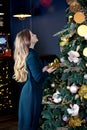 Cute blondie girl in a green woolen dress near an elegant Christmas tree