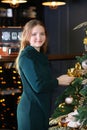 Cute blondie girl in a green woolen dress near an elegant Christmas tree