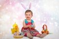 A cute, blue eyed baby girl with bunny ears on her hand on a easter egg hunt