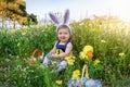 A cute, blue eyed baby girl on a easter egg hunt ourdoors in the meadow