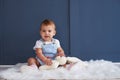 Cute blue-eyed baby girl with toy sitting on the floor Royalty Free Stock Photo