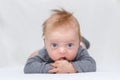 Cute blue-eyed happy infant baby boy laying on the tummy and looking at camera copy space Royalty Free Stock Photo