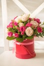 Cute bouquet of pink and beige roses in a red box on a light background. Royalty Free Stock Photo