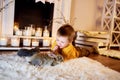 a cute boy admiring grey rabbits in a warm candle light room.