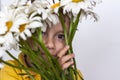 A cute boy with a beautiful bouquet of large daisies. Portrait of a child, funny and cute facial expression. Selective focus Royalty Free Stock Photo
