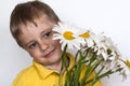 A cute boy with a beautiful bouquet of large daisies. Portrait of a child, funny and cute facial expression. Selective focus Royalty Free Stock Photo