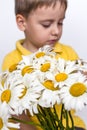 A cute boy with a beautiful bouquet of large daisies. Portrait of a child, funny and cute facial expression. Selective focus Royalty Free Stock Photo