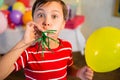 Cute boy blowing party horn during birthday party