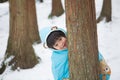 Cute boy in blue cloak playing hide and seek in forest after snow Royalty Free Stock Photo