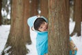 Cute boy in blue cloak playing hide and seek in forest after snow Royalty Free Stock Photo