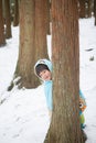 Cute boy in blue cloak playing hide and seek in forest after snow Royalty Free Stock Photo