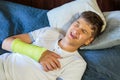 Cute boy with broken hand hearts. Close up young handsome Teenage with elbow plaster at home