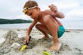 Cute boy building sand tower with seashells use scapula resting at summer sea beach tropical resort