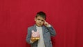 Cute boy in business suit holding piggy bank and getting an idea how to earn more money. Steals the piggy bank. Royalty Free Stock Photo