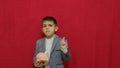 Cute boy in business suit holding piggy bank and getting an idea how to earn more money. Steals the piggy bank. Royalty Free Stock Photo