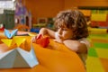 Cute boy child playing handmade origami paper boat at childcare center