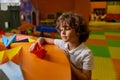 Cute boy child playing handmade origami paper boat at childcare center