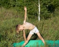 Cute boy child practices yoga in Utthita Trikonasana, extended triangle pose. Kids healthy lifestyle, children yoga
