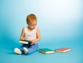 Cute boy chooses what to read from three books Royalty Free Stock Photo