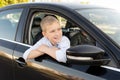 A cute boy climbed out of the car window and laughs. Drive in the car and look out the window Royalty Free Stock Photo