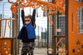 Cute boy is climbing on the playground in the schoolyard. He has a very happy face and enjoy this adventure sports alone outdoor. Royalty Free Stock Photo