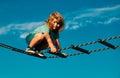 Cute boy climbs up the ladder on the playground. Child climbs up the ladder against the blue sky. Beautiful smiling cute Royalty Free Stock Photo