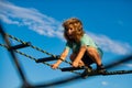 Cute boy climbs up the ladder on the playground. Child climbs up the ladder against the blue sky. Young boy exercise out Royalty Free Stock Photo