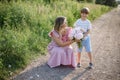 Cute boy congratulates his mother, gives her bouquet of peonies on summer day on country road. Royalty Free Stock Photo