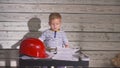 Cute Boy Constructor In Working Clothes and Helme. boy engineer working on a project with a hammer in his hands. On the