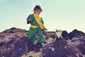 Cute boy with curly blond hair playing with plush fox toy above pile of earth wearing green clothes and yellow scarf