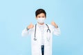 Cute boy doctor wearing medical mask and giving thumbs up Royalty Free Stock Photo