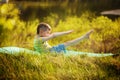 Cute boy doing sports on nature background. Sporty little boy doing exercises in the summer park.