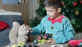 Cute boy dressed as elf petting his soft toy squirrel and assembling toys in santa's workshop Royalty Free Stock Photo