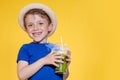 Cute boy Drink Mojito cocktail From Plastic Cup Over Yellow Studio Background Royalty Free Stock Photo