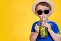 Cute boy Drink Mojito cocktail From Plastic Cup Over Yellow Studio Background Royalty Free Stock Photo