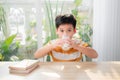 Cute boy drinking glass of milk sitting at a table after doing the homework Royalty Free Stock Photo