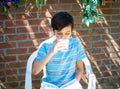 Cute boy drinking milk in the garden.