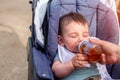 Cute boy drinks juice from a bottle while sitting in a baby carriage Royalty Free Stock Photo